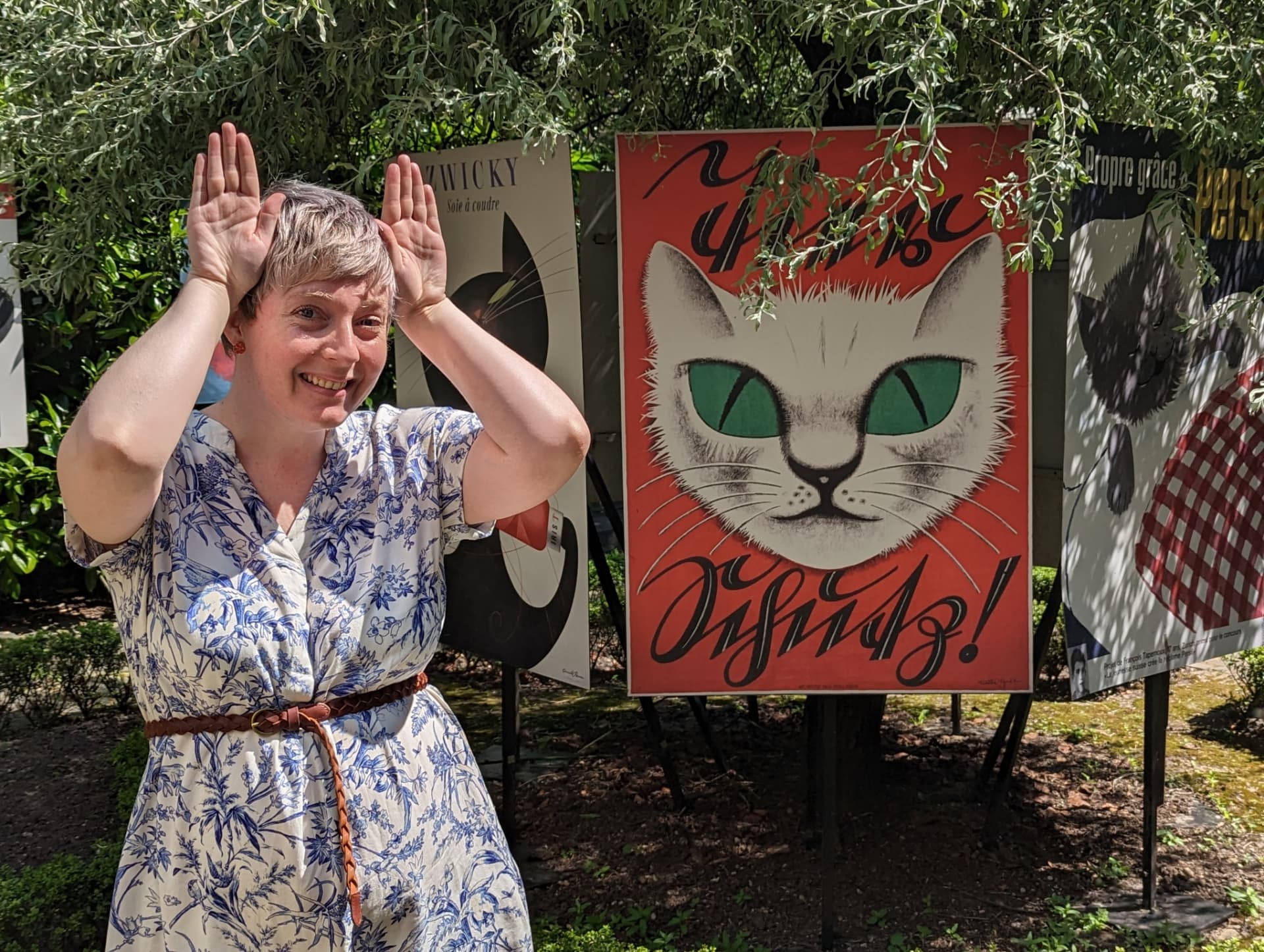 Vickie making cat ears with her hands in front of a cat-themed poster